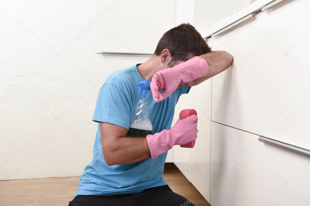 young lazy house cleaner man washing and cleaning the kitchen tired in stress 