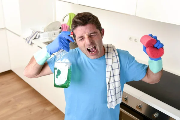 Молодий ледачий прибиральник будинку миє та прибирає кухню пляшкою з розпилювачем — стокове фото