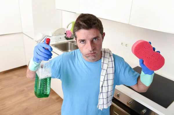 Joven casa perezoso limpiador hombre lavado y limpieza de la cocina con detergente botella de aerosol — Foto de Stock