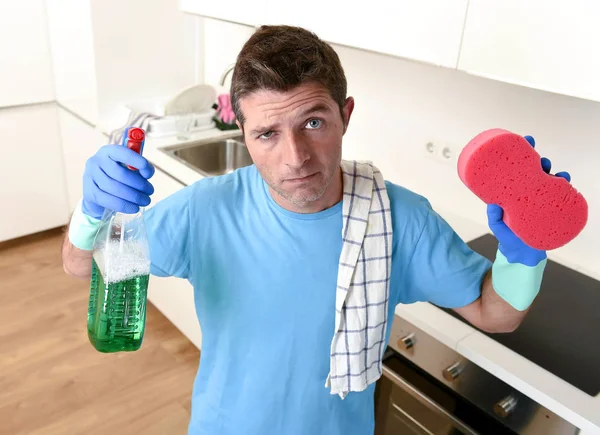 Joven casa perezoso limpiador hombre lavado y limpieza de la cocina con detergente botella de aerosol — Foto de Stock