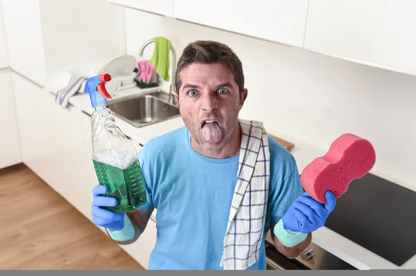 Молодой ленивый уборщик дома моет и чистит кухню бутылкой с моющим средством — стоковое фото