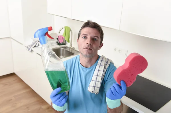 Young lazy house cleaner man washing and cleaning the kitchen with detergent spray bottle — Stock Photo, Image