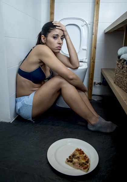 Joven triste y deprimida bulímica mujer sintiéndose mal culpable después de vomitar pizza en WC inodoro —  Fotos de Stock