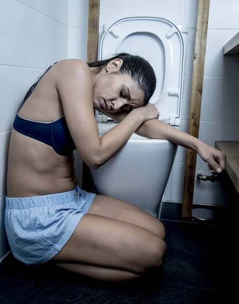 Giovane donna bulimica triste e depressa che si sente male seduta sul pavimento del bagno appoggiata al WC — Foto Stock