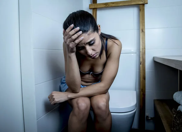 Muda sedih dan tertekan bulimia wanita merasa sakit duduk di toilet WC tampak putus asa dan sakit — Stok Foto