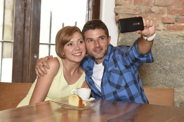 Para biorąc selfie zdjęcie z telefonu komórkowego w kawiarni uśmiechający się szczęśliwy w koncepcja miłość romance — Zdjęcie stockowe