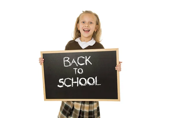 Écolière souriant heureux tenant et montrant petit tableau noir avec texte retour à l'école — Photo