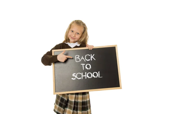Uczennica uśmiechający się zadowolony gospodarstwa i pokazuje małe tablica tekst powrót do szkoły — Zdjęcie stockowe