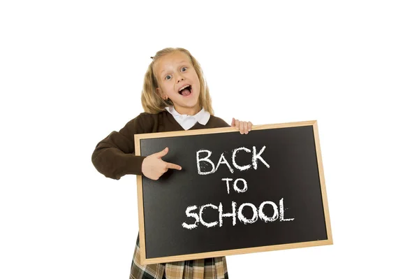 Scolaretta sorridente felice tenuta e mostrando piccola lavagna con testo torna a scuola — Foto Stock