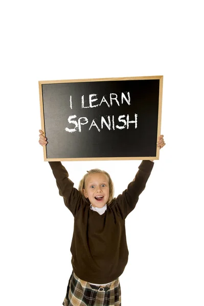 Colegiala sonriendo feliz y alegre sosteniendo y mostrando pequeña pizarra con texto aprendo español —  Fotos de Stock