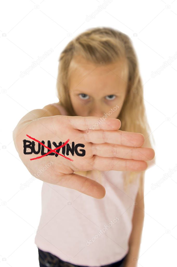 sweet and scared little schoolgirl showing the word bullying scratched written in her hand
