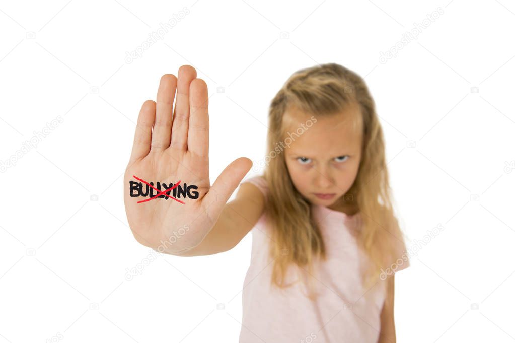 sweet and scared little schoolgirl showing the word bullying scratched written in her hand