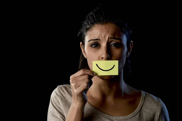 Latina triste deprimida chica latina sosteniendo papel escondiendo su boca detrás de falsa sonrisa dibujada — Foto de Stock