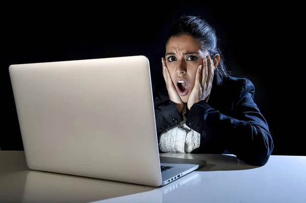 Жінка працює в темряві на портативному комп'ютері пізно вночі здивована шоком і стресом — стокове фото