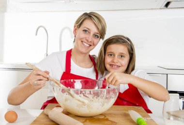 genç anne ve aşçı önlüğü birlikte modern ev mutfak pişirme pişirmek küçük tatlı kız