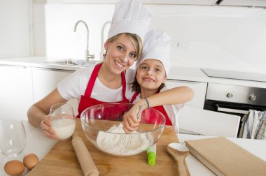 genç anne ve küçük tatlı kızı aşçı şapkası ve birlikte evde mutfak pişirme yemek önlük