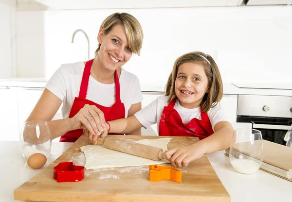 Young mother and little sweet daughter cooking in kitchen preparing desert with rolling pin rod — Stock Photo, Image