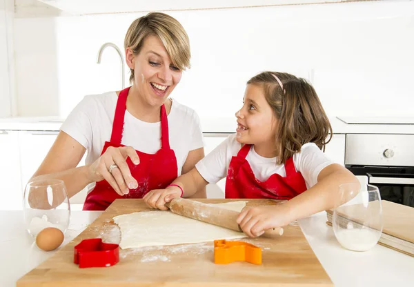 Young mother and little sweet daughter cooking in kitchen preparing desert with rolling pin rod — Stock Photo, Image