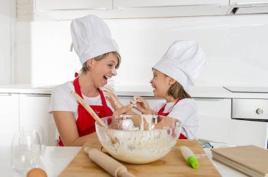 genç anne ve küçük tatlı kızı aşçı şapkası ve birlikte evde mutfak pişirme yemek önlük