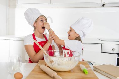 genç anne ve küçük tatlı kızı aşçı şapkası ve birlikte evde mutfak pişirme yemek önlük