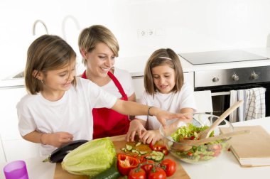aşçı önlüğü ve birlikte salata hazırlamak yemek tatlı güzel İkiz kızları genç anne
