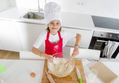 Mini şef aşçı şapkası ve un ve tatlı çöl mutlu gülümseyen hazırlama pişirme yumurta karıştırma önlük kızla