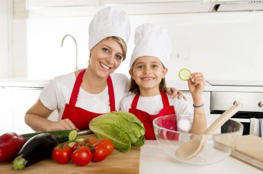 Anne ve küçük kızı şapka önlük hazırlanması ile birlikte evde mutfak yemek salata