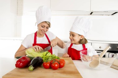 Anne ve küçük kızı şapka önlük hazırlanması ile birlikte evde mutfak yemek salata