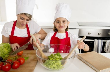 Anne ve küçük kızı şapka önlük hazırlanması ile birlikte evde mutfak yemek salata