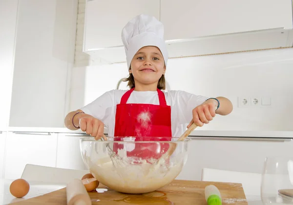 Mini chef girl with cook hat and apron mixing flour and eggs baking preparing sweet desert smiling happy — Stock Photo, Image