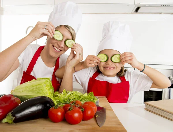 Moeder en dochtertje koken samen spelen met plakjes komkommer op de ogen — Stockfoto