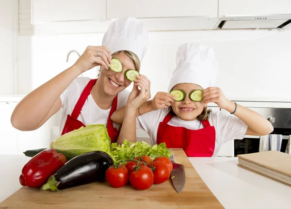 Moeder en dochtertje koken samen spelen met plakjes komkommer op de ogen — Stockfoto
