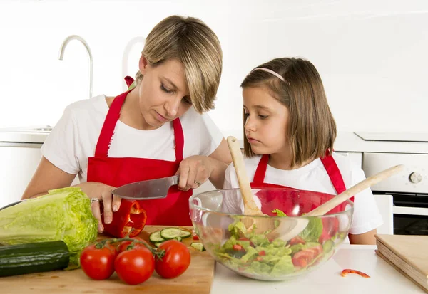 Moeder en dochtertje koken samen met kok schort voorbereiden salade thuis keuken — Stockfoto