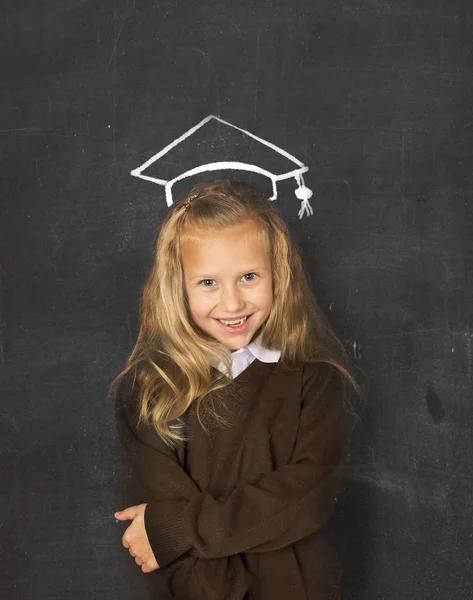 Sweet schoolgirl on blackboard with  with chalk sketch drawing of graduation hat smiling happy — Stock Photo, Image