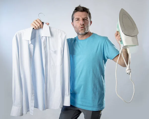 Joven atractivo y satisfecho hombre sosteniendo hierro y camisa pulida sonriendo feliz y arrogante — Foto de Stock