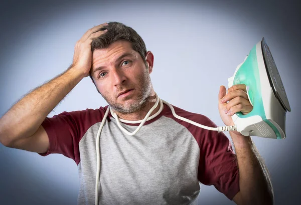 Jovem louco desesperado e frustrado homem fazendo tarefas domésticas segurando ferro — Fotografia de Stock
