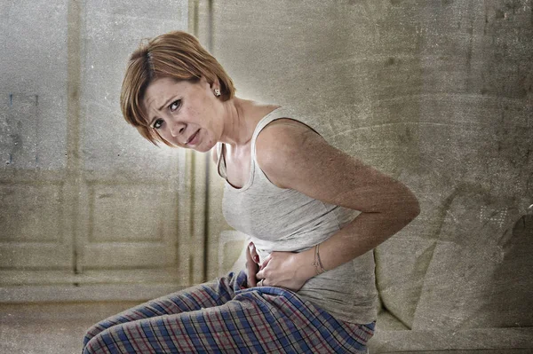 Gadis di sofa memegang sakit perut menderita keram perut edit — Stok Foto