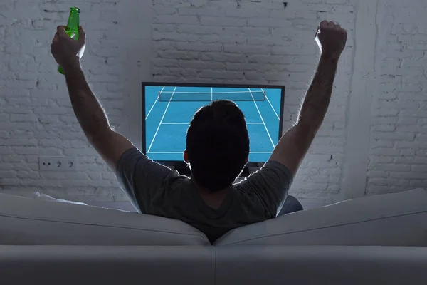 Zadní pohled s mladým mužem domů sám pozoroval grandslamový tenisový zápas v televizi na pohovce — Stock fotografie