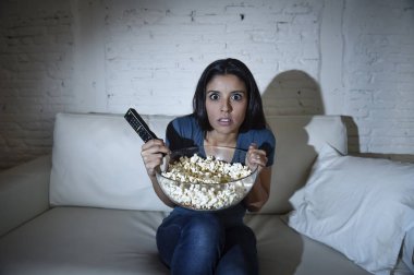 Latin kadın ev kanepe, kanepe oturma odasında gözleri dehşete kapsayan televizyon izlerken