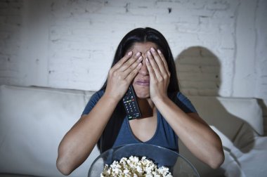 Latin kadın ev kanepe, kanepe oturma odasında gözleri dehşete kapsayan televizyon izlerken
