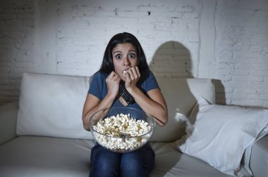 Latin kadın ev kanepe, kanepe oturma odasında gözleri dehşete kapsayan tv izlerken