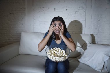 Latin kadın ev kanepe, kanepe oturma odasında gözleri dehşete kapsayan televizyon izlerken