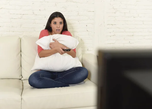 Mujer latina sentada en casa sofá sofá en la sala de estar viendo la televisión miedo película de terror — Foto de Stock