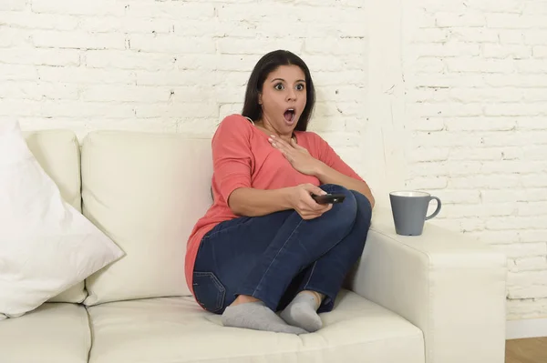 Mujer latina sentada en casa sofá sofá en la sala de estar viendo la televisión miedo película de terror — Foto de Stock