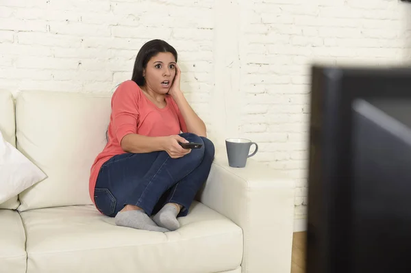 Mujer latina sentada en casa sofá sofá en la sala de estar viendo la televisión miedo película de terror — Foto de Stock