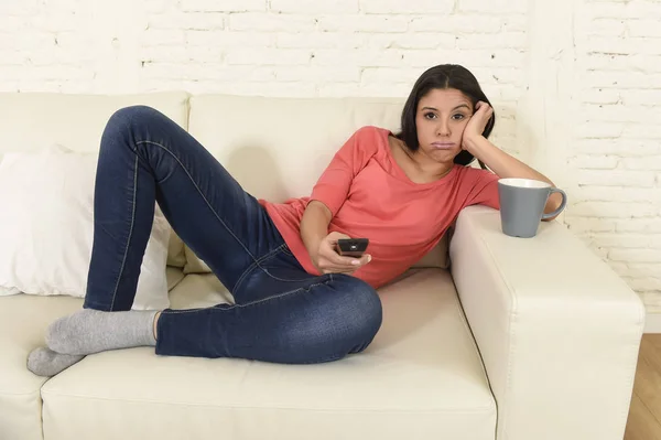 Jovem bela mulher hispânica em casa assistindo televisão cansado e entediado — Fotografia de Stock