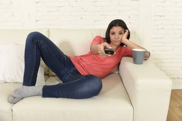 Mladá krásná žena hispánský v domácí sledují televizi, unavený a znuděný — Stock fotografie