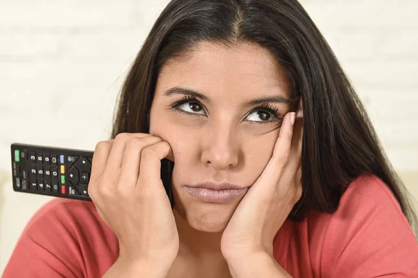 Молода красива іспаномовна жінка вдома дивиться телевізор втомлений і нудний — стокове фото