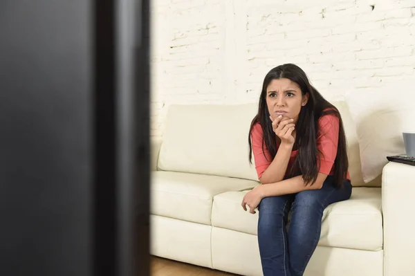 Joven hermosa mujer hispana en casa viendo la televisión cansado y aburrido —  Fotos de Stock