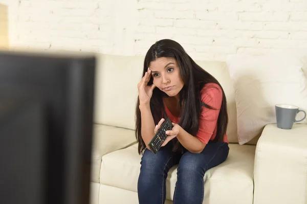 Молода красива іспаномовна жінка вдома дивиться телевізор втомлений і нудний — стокове фото